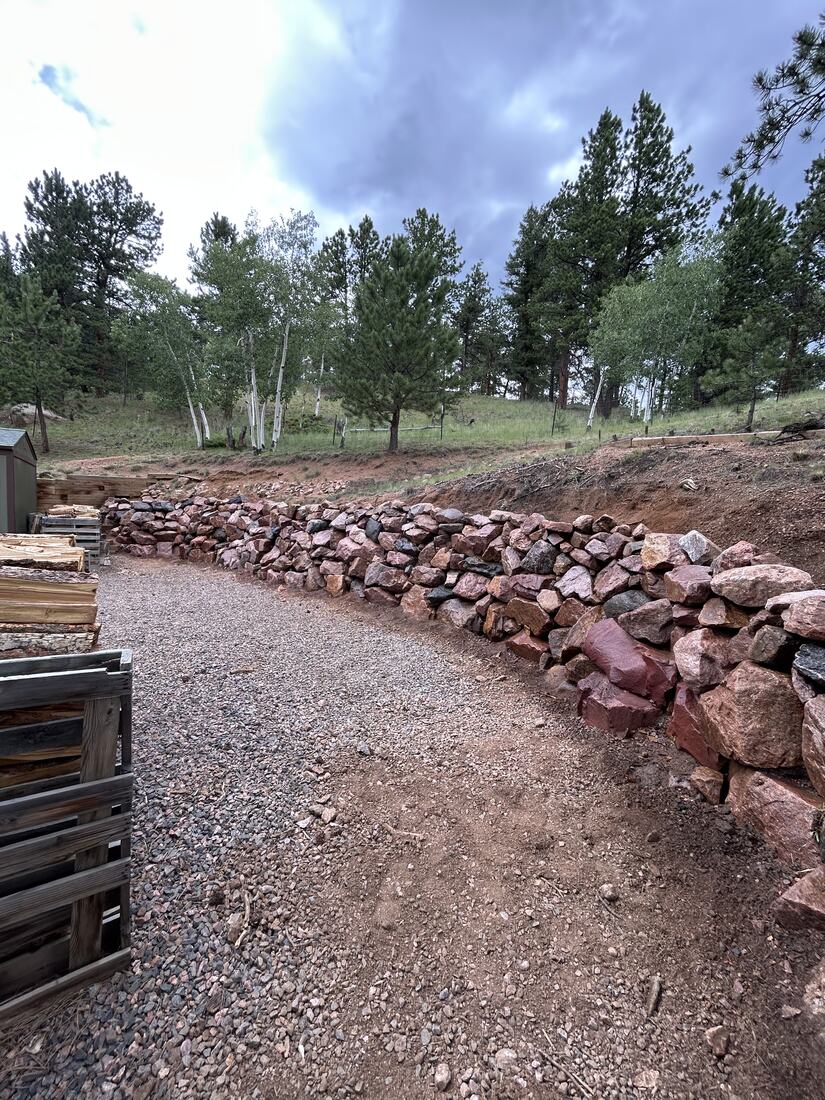 Low natural boulder retaining wall along a gravel driveway