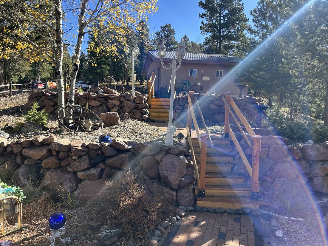 Dry-stacked boulder retaining wall with wood stairway leading to the house