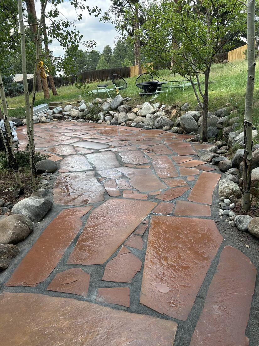 Flagstone patio bordered by rounded river rock among aspen trees