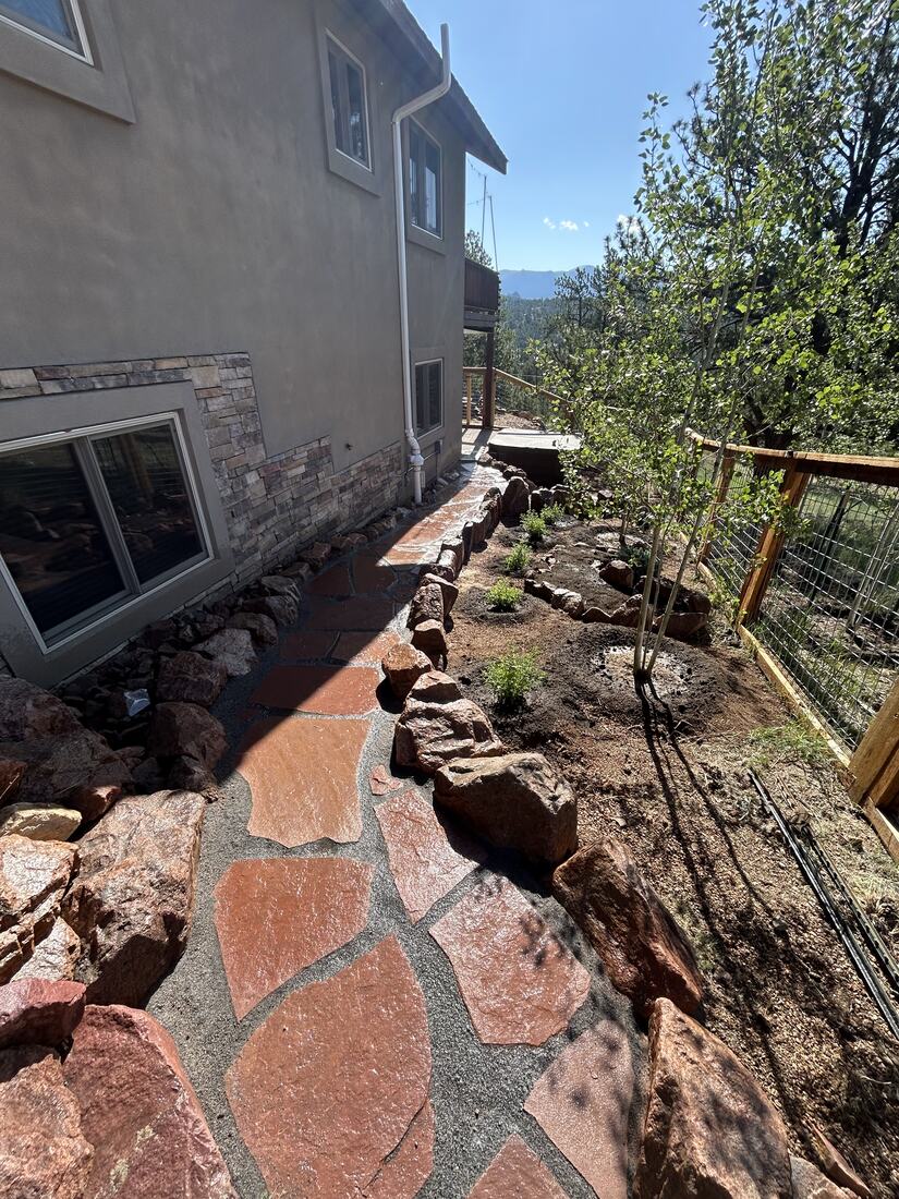 Flagstone walkway with low boulder wall along the side of a mountain home