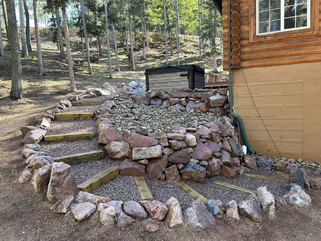 Boulder-lined timber steps beside a log cabin and hot tub