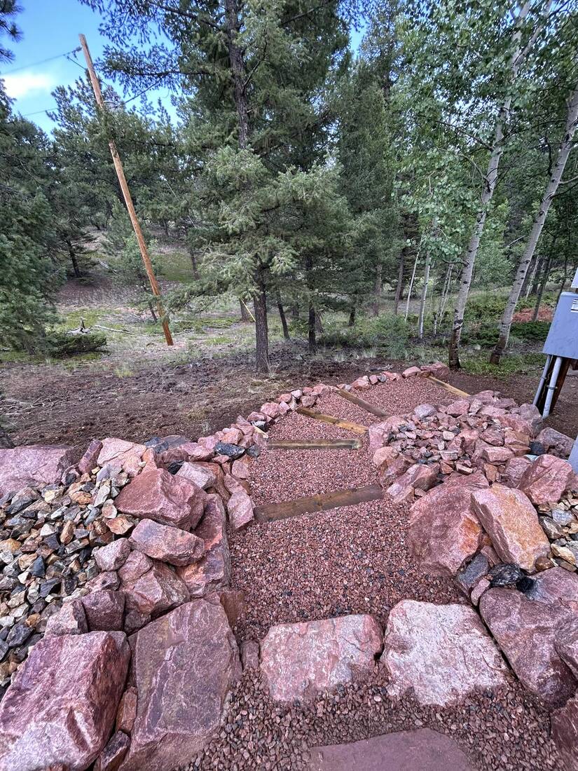Timber tread landing set into a boulder-ringed gravel path