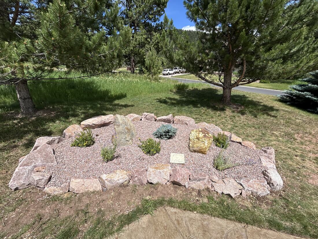 Rounded xeriscape planting bed with boulder border, gravel mulch, and drought-adapted plants